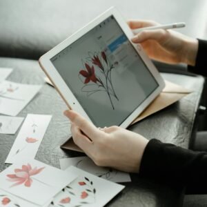 Close-up of hands refining floral sketches on a tablet in a creative studio.